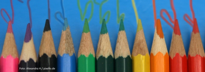 Buntstifte liegen auf einem blauen Hintergrund. Aus den Spitzen der Stifte kommen der jeweiligen Farbe entsprechend Linien.