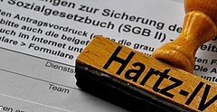 Ein Holzstempel mit dem Aufdruck Hartz-IV liegt auf einem Antragsformular für Leistungen nach dem SGB II. (Foto: K. F. Dominik/ pixelio.de)