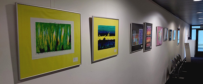Ausstellung farbenfrohe Depression: Blick einen Gang entlang an dessen Wänden farbenfrohe Bilder hängen.