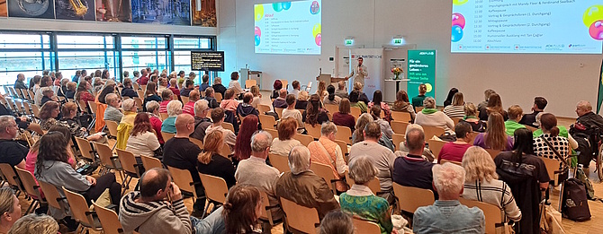 Blick in den Saal der 3. Mitteldeutschen Selbsthilfekonferenz in Leipzig. Teilnehmende sitzen in Reihen und hören einem Redner zu.