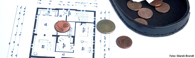 Symbolbild: Auf einem Wohnungsgrundriss liegt Kleingeld