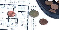 Symbolbild: Auf einem Wohnungsgrundriss liegt Kleingeld