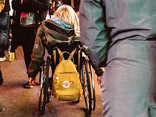 Eine junge Frau fährt mit ihrem Rollstuhl durch Menschenmassen auf einem Weihnachtsmarkt. (Foto: Andy Weiland/ Gesellschaftsbilder.de)