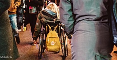 Eine junge Frau fährt mit ihrem Rollstuhl durch Menschenmassen auf einem Weihnachtsmarkt. (Foto: Andy Weiland/ Gesellschaftsbilder.de)