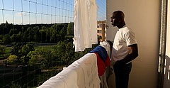 Paul aus Kamerun steht auf dem Balkon und blickt in die Ferne.