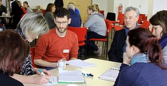 Menschen sitzen um einen Tisch und sprechen über die Erzieherausbildung in Sachsen.