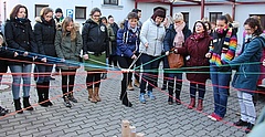 Menschen stehen in einem Kreis und halten Schnüre, die in der Mitte zusammentreffen.