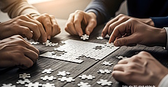 Viele Hände arbeiten gemeinsam an einem Puzzle.
