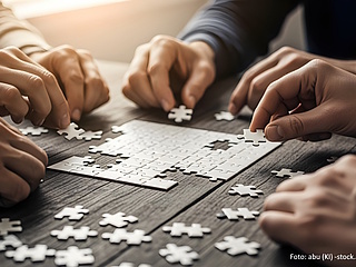 Viele Hände arbeiten gemeinsam an einem Puzzle.