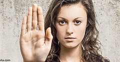 Eine brünette Frau hält ihre Handfläche den Betrachtenden entgegen und signalisiert dadurch ein klares Stopp.
