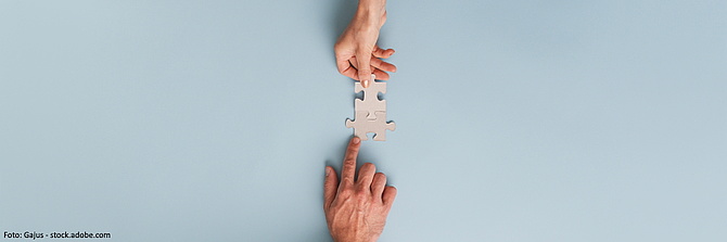 Symbolbild: Zwei Hände fügen zwei Puzzleteile zusammen.