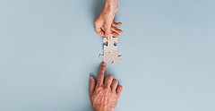 Symbolbild: Zwei Hände fügen zwei Puzzleteile zusammen.