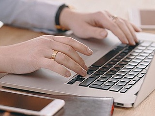 Die Hände einer Person befinden sich über der Tastatur eines Laptops.