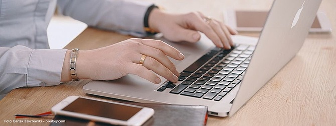 Die Hände einer Person befinden sich über der Tastatur eines Laptops.