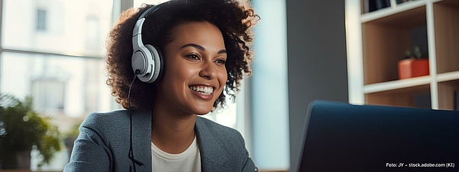 Lächelnde Frau mit Kopfhörern vor Laptop