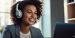 Lächelnde Frau mit Kopfhörern vor Laptop