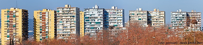 Symbolbild: Verschiedenfarbige Wohnblöcke vor einem blauen Himmel. 