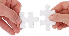 Symbolbild: Zwei Hände setzen zwei Puzzle-Teile zusammen.