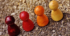 Symbolbild: Vier unterschiedlich farbige Spielfiguren stehen nebeneinander.