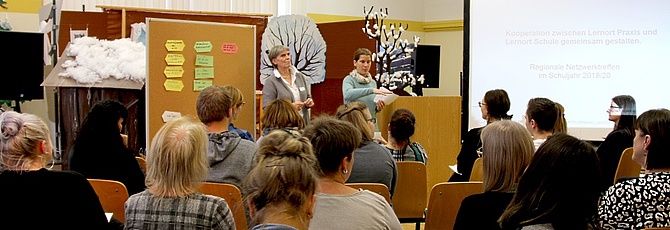 Zwei Frauen stehen in einem Klassenraum vor einem Publikum und sprechen über  Lernortkooperationen.