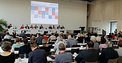 Menschen sitzen in Reihen und blicken zu einem Podium auf der Mitgliederversammlung 2018 des Paritätischen Sachsen.