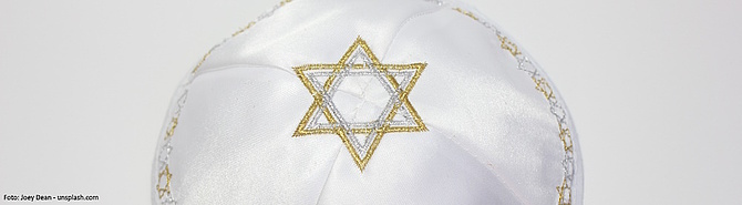 Symbolbild: Eine weiße Kippa mit einem gold-silbern eingesticktem Davidstern