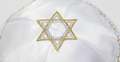 Symbolbild: Eine weiße Kippa mit einem gold-silbern eingesticktem Davidstern